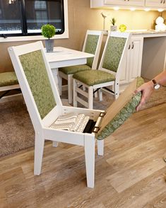 a person is opening up a chair in the middle of a room with white cabinets and green chairs