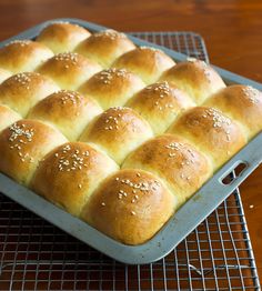 a baking pan filled with bread on top of a cooling rack and topped with sesame seeds