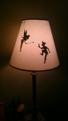 a lamp shade with the shadow of tinkerbell on it