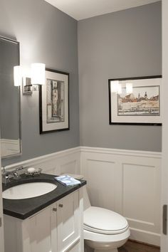 a white toilet sitting next to a sink in a bathroom under a framed picture on the wall