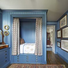 a bedroom with blue walls and wooden flooring has a canopy bed in the middle