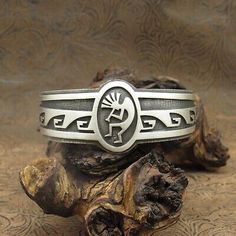 (eBay) Sterling silver cuff bracelet. This Hopi overlay bracelet has kokopelli and wave designs. It carries the artist initials (ES) belonging to Elgene Sehongva. The overlay kokopelli design is 1 3/16" in the front and tapers to 5/8" in the back. Handmade Southwestern Cuff Bracelet As Gift, Artisan Stamped Cuff Bracelet As Gift, Artisan Stamped Cuff Bracelet Gift, Symbolic Stamped Cuff Bracelet, Artisan Cuff Bracelet Gift, Southwestern Engraved Cuff Bracelet As A Gift, Southwestern Stamped Cuff Bracelet As Gift, Southwestern Stamped Cuff Bracelet For Gift, Southwestern Stamped Bracelets As Gift