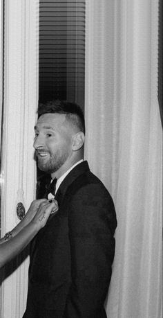 a man and woman standing next to each other in front of a curtained window