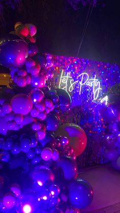 balloons are lit up in purple and blue at the end of a night time party