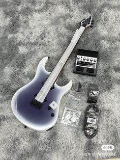 an electric guitar laying on top of a carpet next to other items and accessories in plastic bags