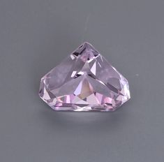 a pink diamond sitting on top of a gray table next to a white wall and floor