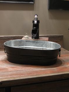 a large metal bowl sitting on top of a wooden table next to a wall mounted camera