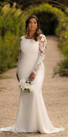 a woman in a wedding dress standing on a dirt road