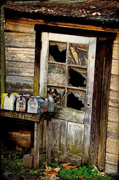 an old run down building with broken windows and mail boxes in front of the door