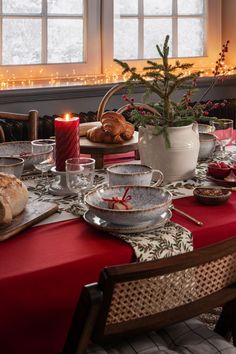 a table set for christmas dinner with bread and candles