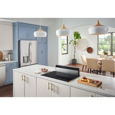 a kitchen with blue cabinets and white counter tops, an island in the middle has a potted plant on it