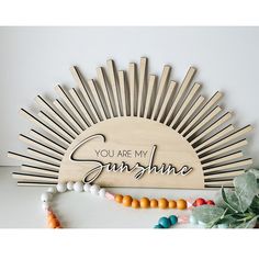 a wooden sign that says you are my sunshine with beads around it and a sunburst