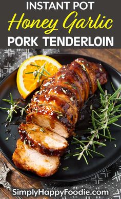 honey garlic pork tenderie on a black plate with orange slices and rosemary sprigs