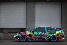 a colorful car parked in front of two garage doors with graffiti on the paint job