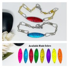 four different colors of necklaces with chains and flowers next to them on a white surface