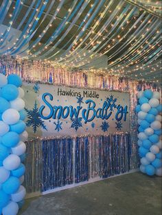 balloons and streamers are hanging from the ceiling in front of a snow ball backdrop