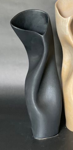 two vases sitting next to each other on a gray surface with no one in it