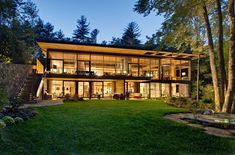 a large house sitting in the middle of a lush green field next to a forest