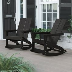 two black rocking chairs sitting on top of a wooden floor next to a planter