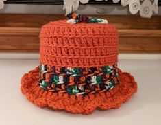 an orange crocheted hat is sitting on a table