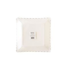 a square white plate with scalloped edges and a label on the side that says,