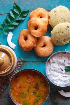 some food is sitting on a blue table and there are two bowls of soup next to it