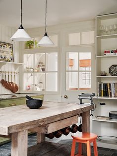 a kitchen with an old table and stools in it's center island, surrounded by bookshelves