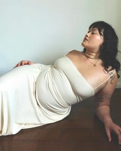 a woman laying on the floor wearing a white dress