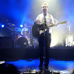 a man standing on top of a stage holding a guitar