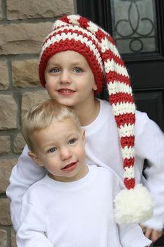 two young boys wearing knitted hats and scarves, standing next to each other