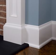 the corner of a room with blue walls and white trim on the wall, along with a black mat