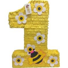 the number one is made out of yellow tin foil with flowers and a bee on it