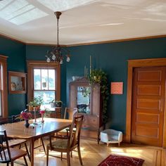 a dining room with blue walls and wooden floors is pictured in this image, there are many chairs around the table