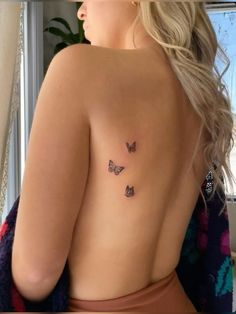 the back of a woman's body with three butterflies on her left shoulder and chest