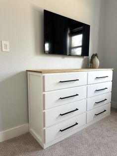 a flat screen tv mounted on top of a white dresser