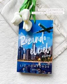 a book sitting on top of a bed next to a white tulip and an airplane