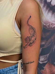 a woman's arm with a tiger tattoo on the left side of her body