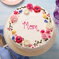 a white cake with flowers and the word mom written on it