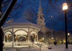 a gazebo in the middle of a snowy park at night with lights on it