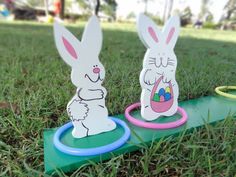 two easter bunnies sitting on top of a green field next to a frisbee