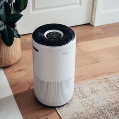 an air purifier sitting on the floor next to a potted plant