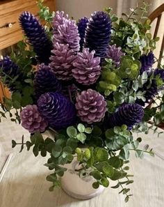 purple and green flowers in a white vase on a table