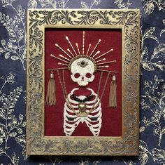 a skeleton in a gold frame with tassels on it