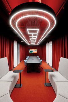 a conference room with red curtains and white couches in front of a large table