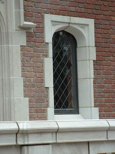 a bird sitting on the ledge of a brick building with a window in it's center