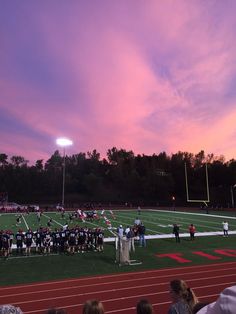 a football game is being played on a field with people in the stands watching it