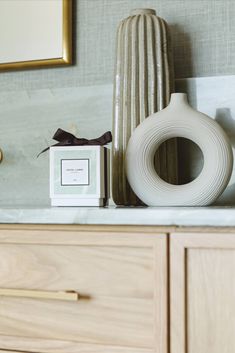 a white vase sitting on top of a counter next to a box with a brown ribbon