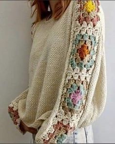 a woman wearing a sweater with crocheted flowers on it