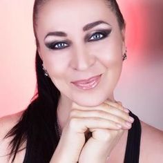 a woman with long black hair and blue eyes smiling at the camera while posing for a photo