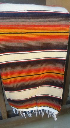 a multicolored blanket sitting on top of a wooden bench